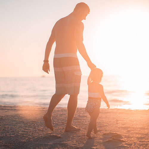 Photo of father and daughter walking on beach