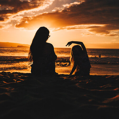 Photo of mother and daughter on beach at sunset